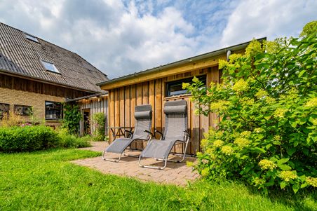 Hausansicht mit Liegestühlen im Garten