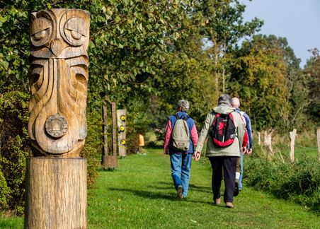 Personen spazieren an Eulenskulpturen vorbei