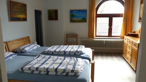 Zwei zusammenstehende Betten, Kommode, Durchgang zum 2. Schlafzimmer
