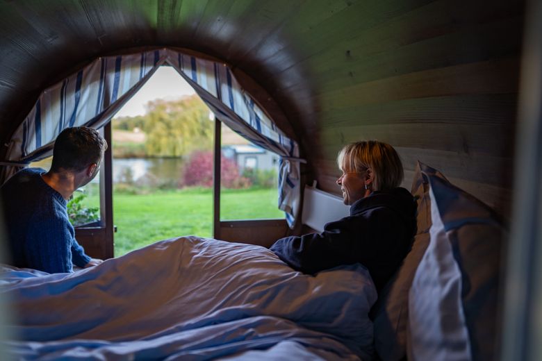 Zwei Personen sitzen auf einem Bett in einem umgebauten Rumfass