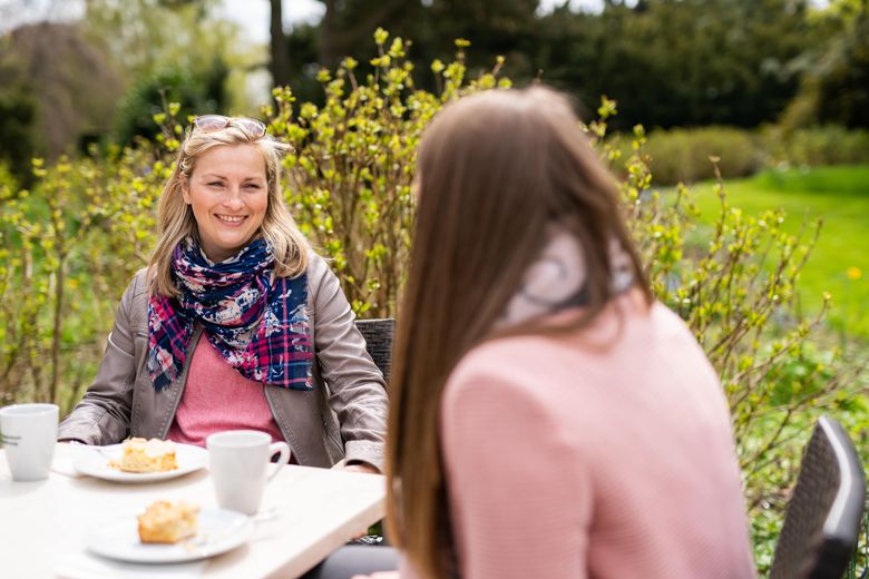 Zwei Frauen sitzen am Tisch bei Kaffee und Kuchen