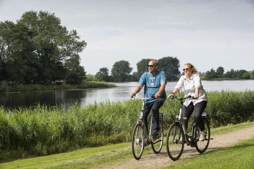 Zwei Radfahrer fahren entlang eines Flußes