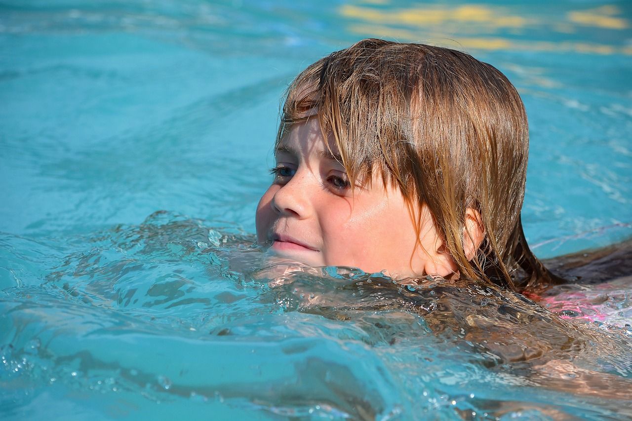 Ein Kind schwimmt im Wasser und bewegt sich spielerisch vorwärts.