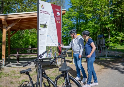 Zwei Radfahrer stehen vor einer Infotafel