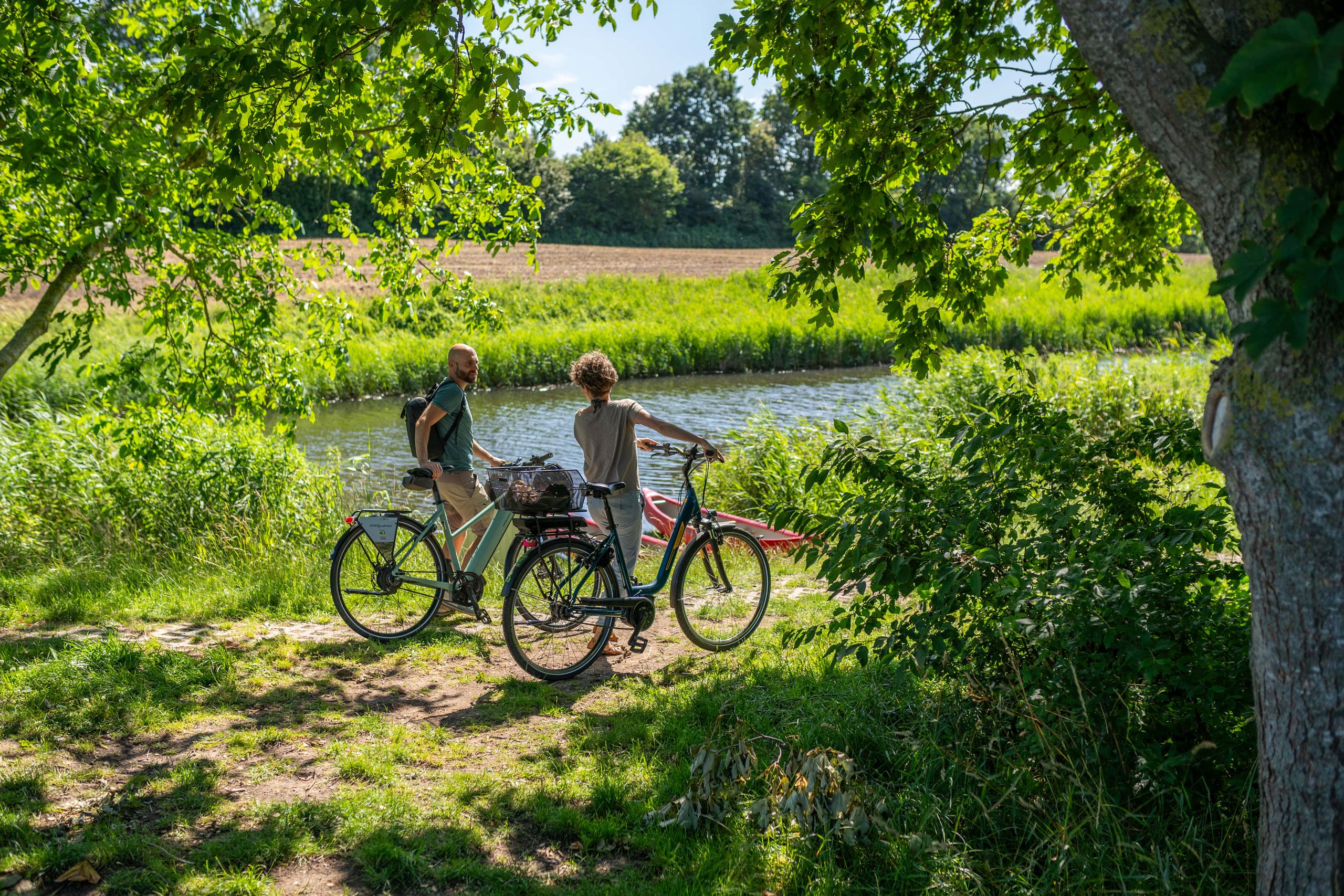Zwei Radfahrer stehen am Rand eines Flusses