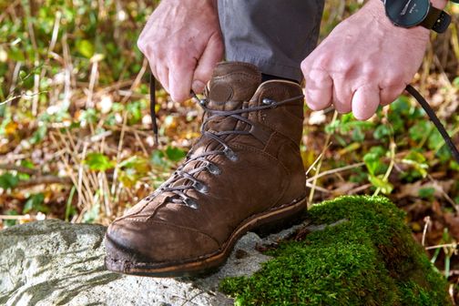 Ein Wanderer schnürt sich die Schuhe