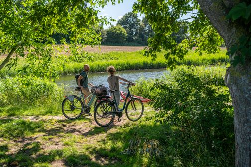 Zwei Radfahrer stehen am Rand eines Flusses