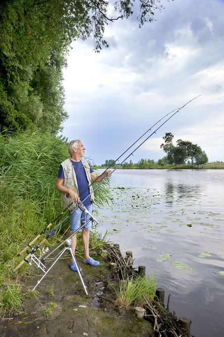 Angler steht neben seiner Angel