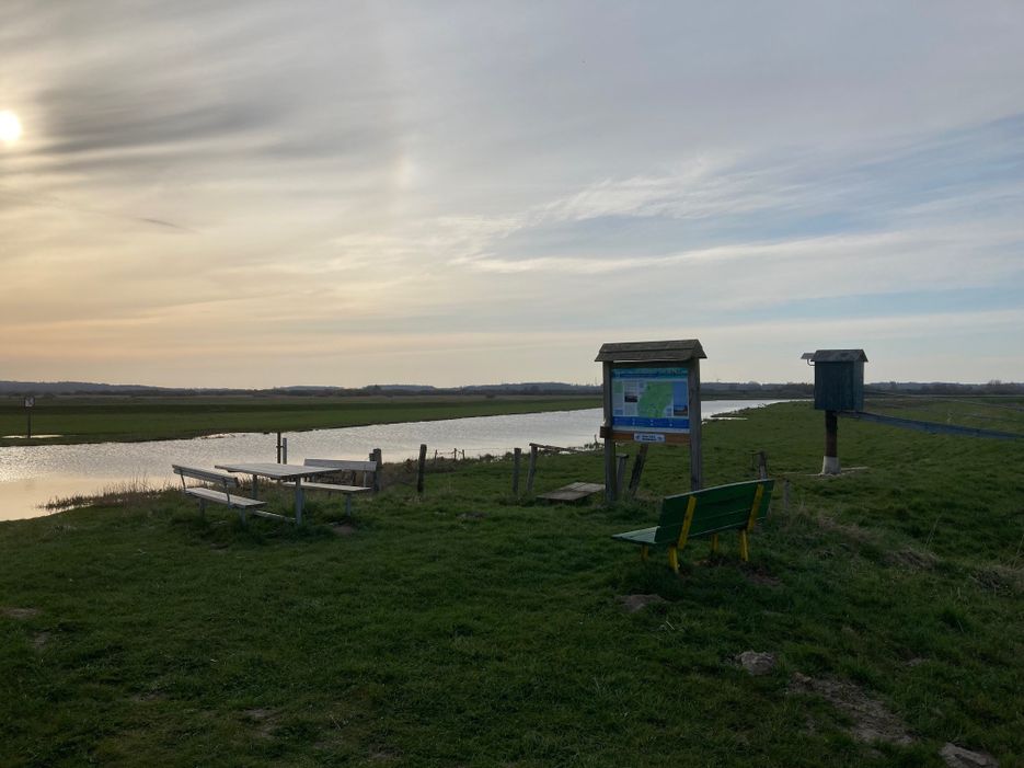 Rastplatz mit Sitzmöglichkeit und Infoschild direkt am Wasser