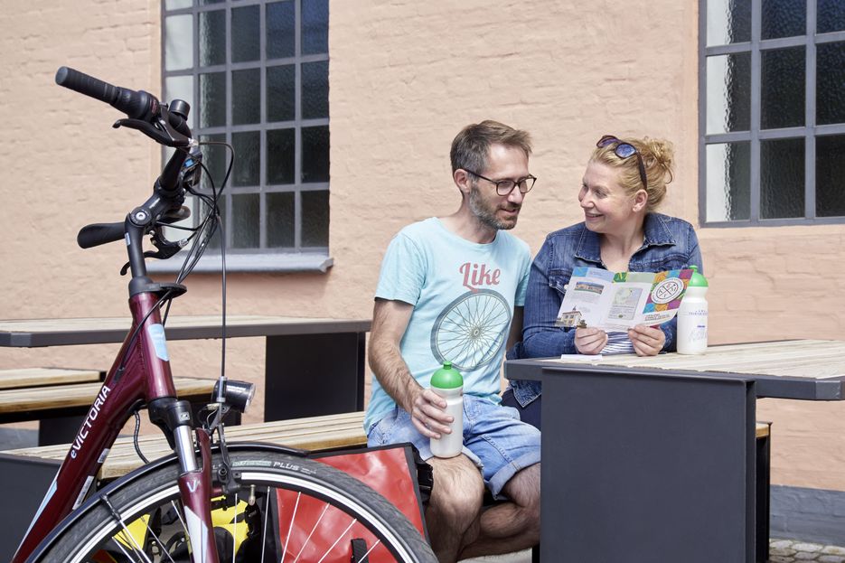 Pärchen sitzt auf Bank und schaut sich Flyer an