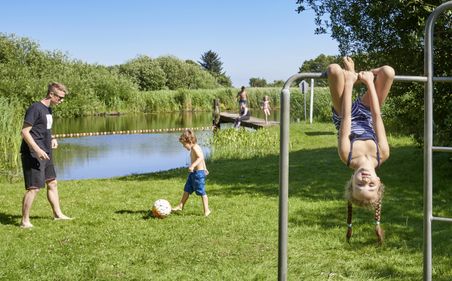 Familie spielt auf Rasen vor Badestelle