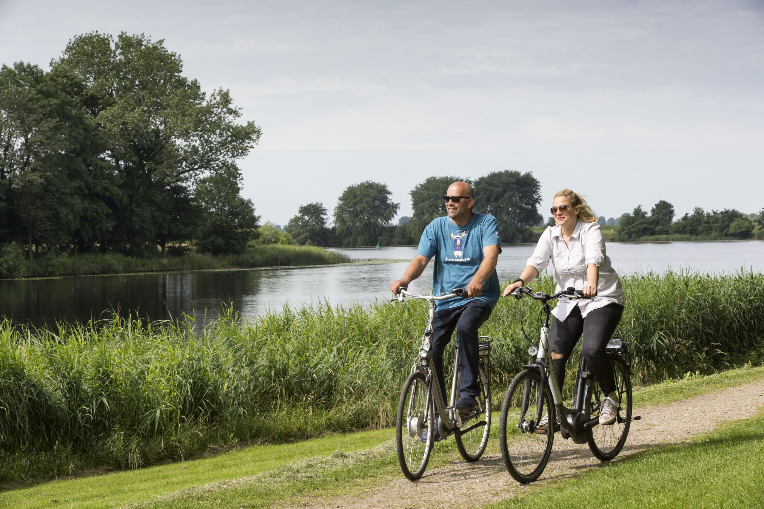 Zwei Radfahrer fahren entlang eines Flußes