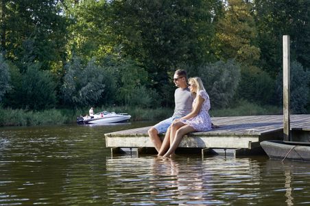 Paar sitzt auf Steg am Wasser