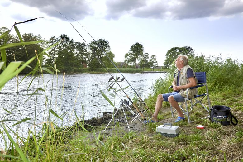 Angler sitzt am Ufer
