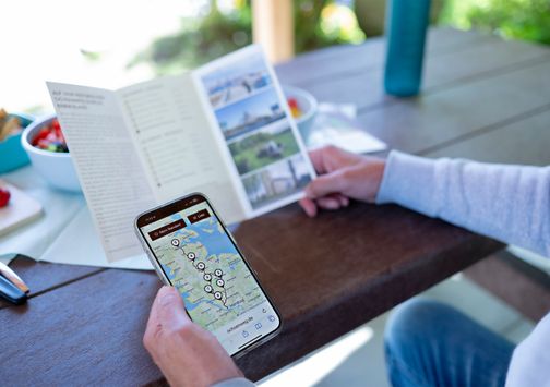 Route mit Handy und Prospektmaterial abgleichen