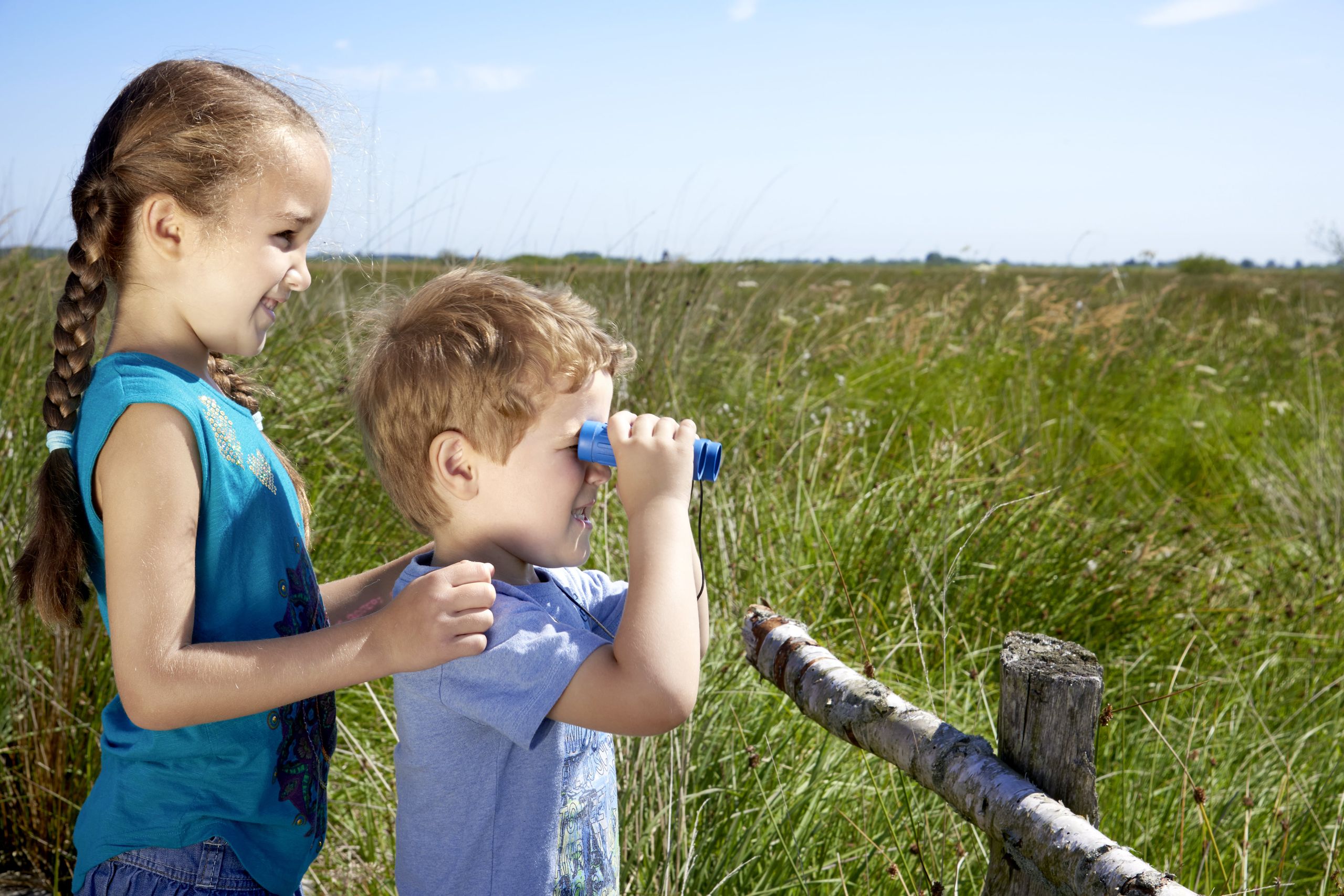 Zwei Kinder mit Fernglas in der Natur