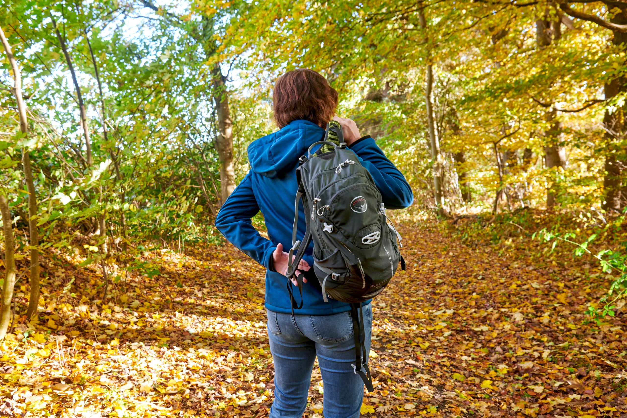 Eine Frau setzt sich einen Rucksack auf