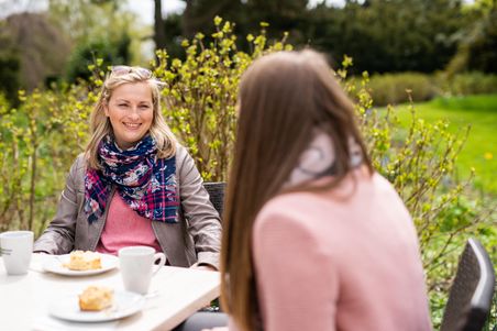 Zwei Frauen sitzen am Tisch bei Kaffee und Kuchen