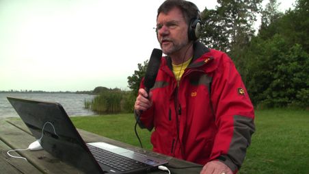 Mann mit Mikro und Laptop am See